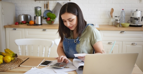 young beautiful woman working on calculator sitting on chair with laptop and papers on table