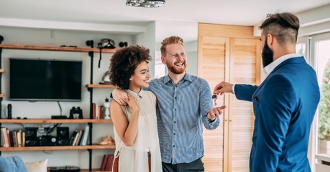 happy couple getting keys from realtor in suit