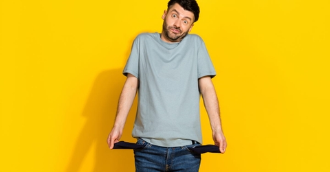 young man standing in front of yellow background showing empty pockets