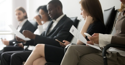 multi ethnic applicants waiting for their call using smartphones and holding papers