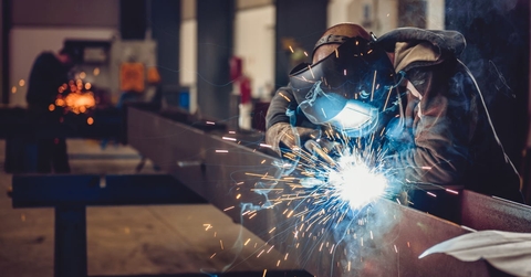 male worker using torch to weld metal at work