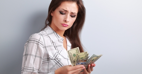 unhappy woman looking on dollars and thinking
