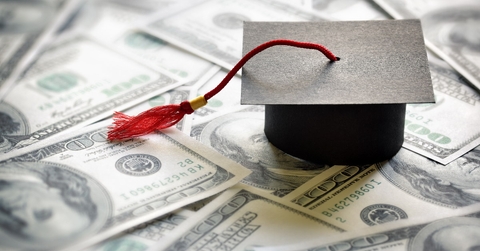 graduation cap on top of one hundred dollar bills  