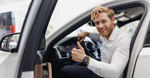 smiling man getting out of the car with a thumbs up