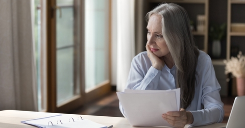elderly retired woman thinking over paper documents