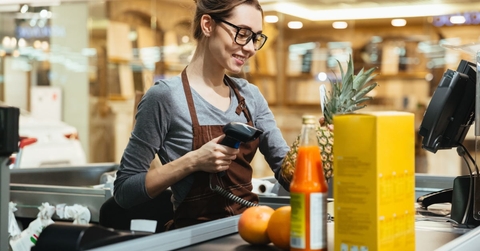 happy female cashier at store scanning grocery items