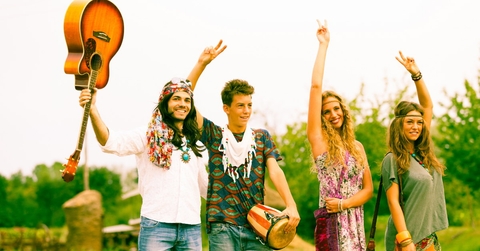 hippie friends standing on road in countryside holding drums and instruments