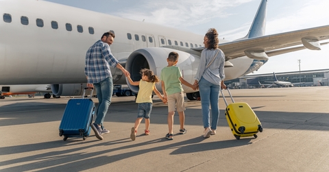 smiling parents and kids walking with travel bags