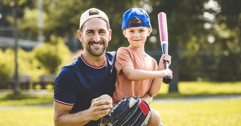 father and son playing baseball in sunny day at public park
