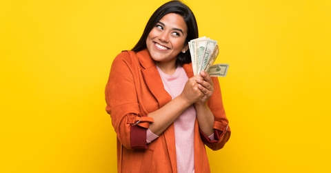 happy woman wearing brown long coat flaunting money 