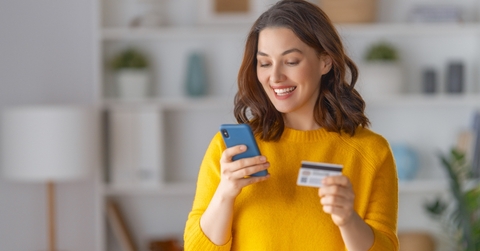 Very happy woman holding phone and credit card