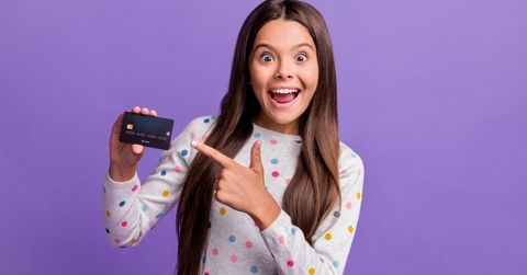 happy teenage girl smiling while pointing towards card in hand