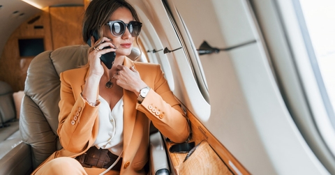 elegant woman wearing suit sitting on private jet talking on phone