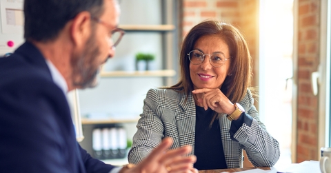 confident businessman explaining ideas to business woman sitting at table with papers in office