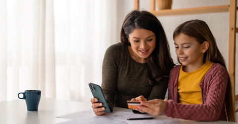 young woman using a mobile phone and a credit card with her daughter
