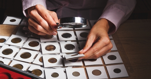 old coin in the woman’s hand through the magnifying glass