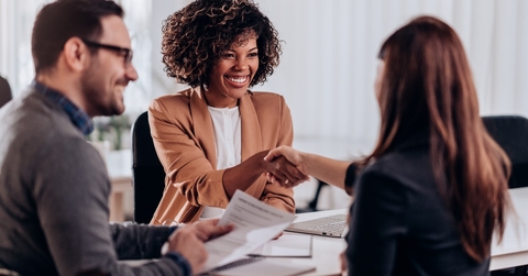 A female candidate receiving congratulations from a female interviewer after a successful job interview.