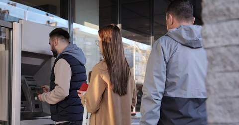 people waiting for their turn to use atm in street