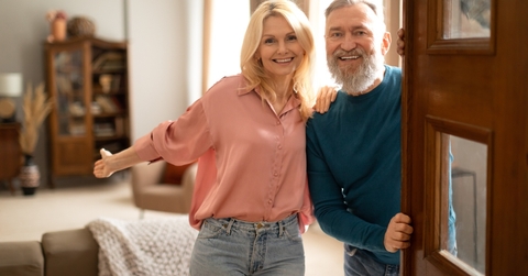 Happy senior couple holding opened door