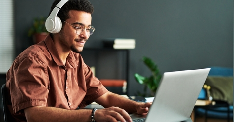 Man using laptop while wearing headphones