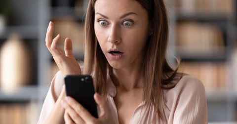 woman shocked at news on smartphone