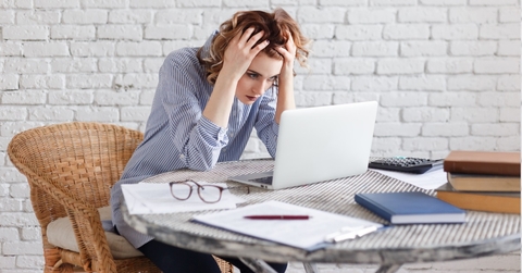 frustrated woman holding head with laptop