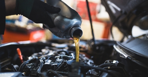 mechanic pouring oil into car engine