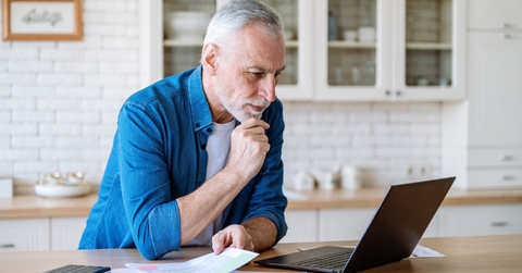 senior man reviewing taxes using laptop