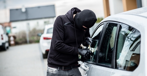 thief breaking car window using screwdriver