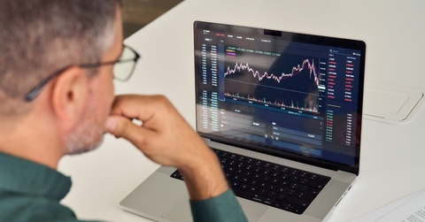 male broker analysing graphs on laptop