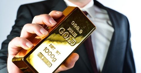 businessman holding 100g fine gold bar