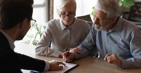 pensioners sitting at desk signing