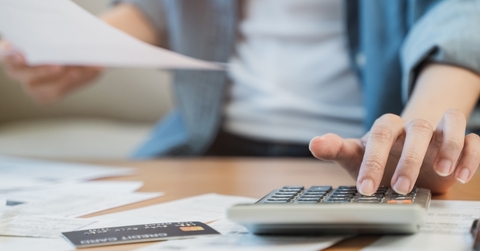 stressed woman reviewing debt using calculator