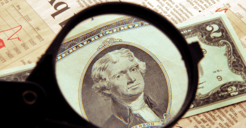 $2 bill being examined with magnifying glass