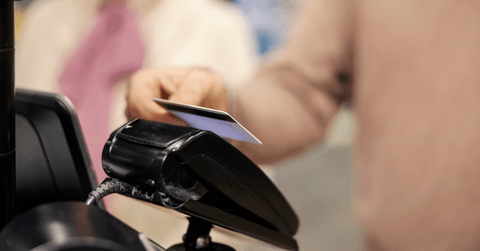 Close up of a senior man paying with credit card on self-service cash register in supermarket
