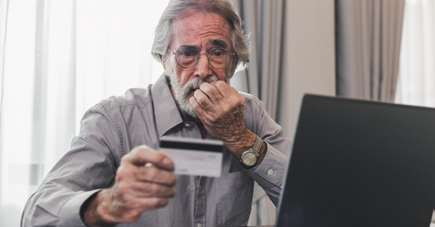 upset senior man holding credit card