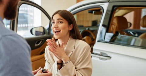 happy woman receiving car key at dealership