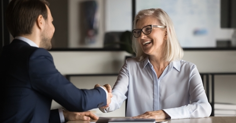 businesswoman shaking hands with younger business colleague