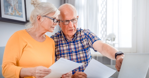 Worried senior couple checking bills using laptop