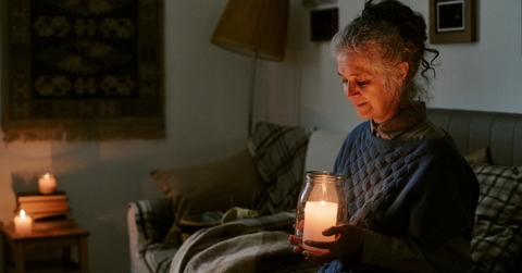 woman sitting on sofa holding large candle jar