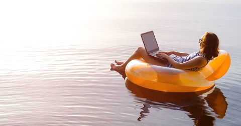 Woman working on a laptop in an inflatable ring in the pool