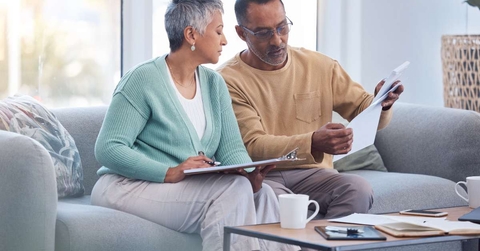 couple on sofa with bills paperwork and insurance 