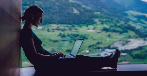 Woman in a scenic location working on a laptop