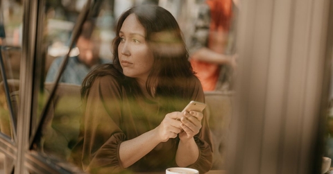 Gen X woman looking pensively out a window at a cafe