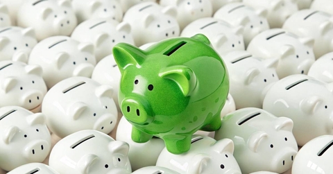 Green piggy bank standing out among white piggy banks 