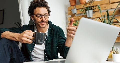 man with coffee mug working on laptop from home