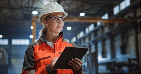 woman in a hard hat with a tablet working in a warehouse