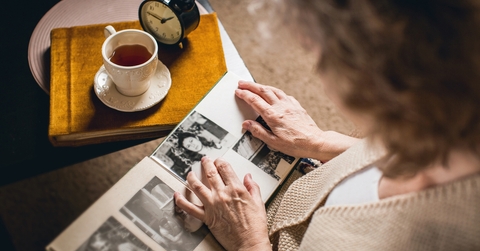 elderly woman looks at the picture in the album