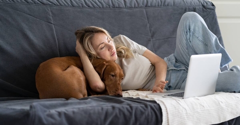 Woman working from home on couch with dog