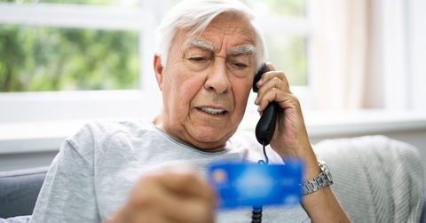 senior man calling while holding credit card